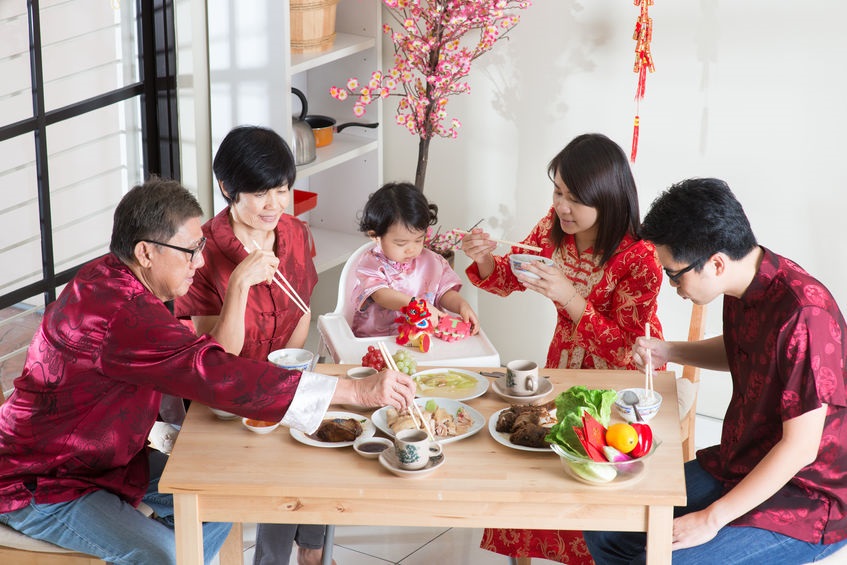 Chinese-family-of-five-wearing-traditional-Chinese-clothing-seated-together-at-a-dining-table-sharing-a-meal-as-part-of-a-communal-eating-tradition.